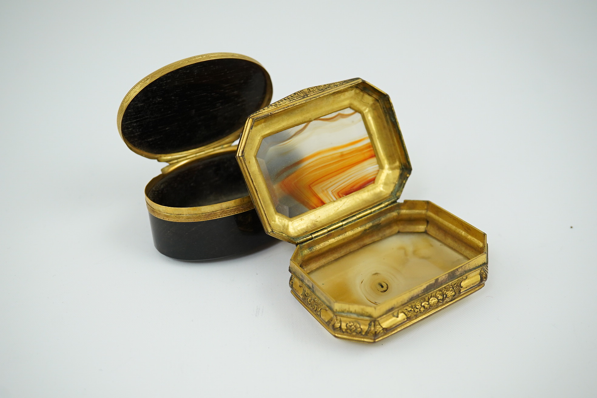 An early 19th century German gold mounted rutile agate? oval snuff box, 64mm and another gilt copper mounted agate snuff box.